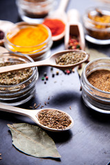 Spices on black background in special jars. Food