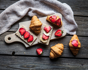 A delicious breakfast of strawberries and bread on wooden background. Fruit, food, sandwiches, cheese. Vintage style.
