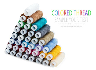 Pyramid of the Sewing multi colored thread isolated on white. Text for example, and can be easily removed. Focus in the middle of the frame
