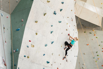 Sporty young woman exercising in a colorful climbing gym