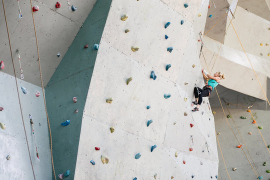 Sporty young woman exercising in a colorful climbing gym