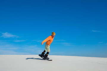 Fototapeta na wymiar Man making a trick on snowboard on sand slope