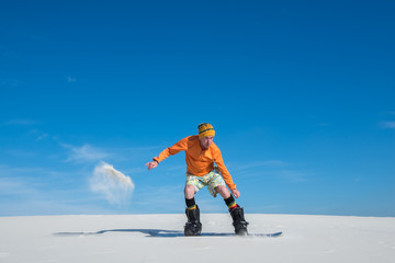Naklejka na ściany i meble Snowboarder is landing after the jump on sand slope.