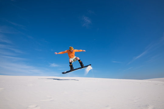 Snowboarder is flying over the sand dune.