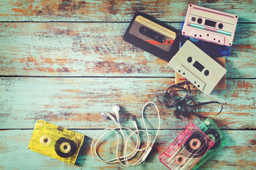 Top view (above) shot of retro tape cassette with earphone on wood table - vintage color effect styles. - obrazy, fototapety, plakaty