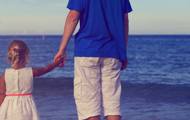father and daughter holding hands at beach