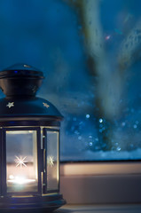 lantern with a candle in it near the window.