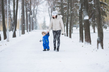 Mother and little toddler boy walking in the winter forest