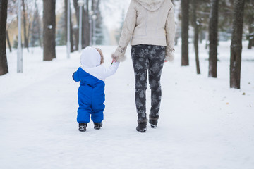 Fototapeta na wymiar Mother and little toddler boy walking in the winter forest