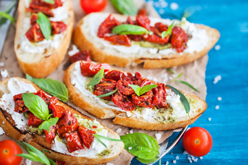 Bruschetta with cream cheese, pesto, fresh basil and sun dried t