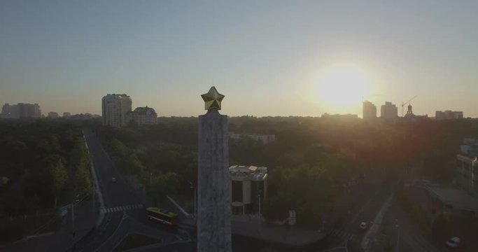 Aerial camera moves towards the star on top of the Wings of Victory monument in the Arcadia district of Odessa Ukraine as the sun rises behind