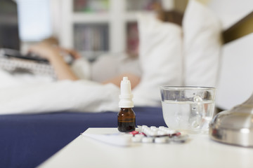 Tablets, drops, thermometer on the nightstand beside the bed of
