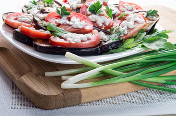 Kitchen table with stewed eggplant and tomato slices