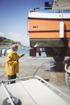Man cleaning boat with pressure washer