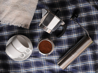 Geyser coffee, grinder and white cups on blue plaid texture
