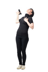 Female spy in black clothes falling backwards and dropping gun while getting shot. Full body length portrait isolated over white studio background.