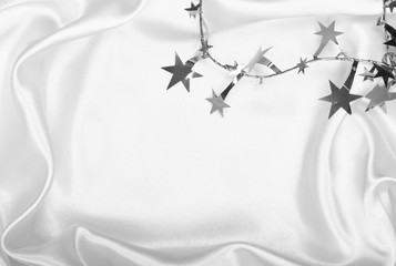Fototapeta na wymiar Silver stars and spangles on white silk as background