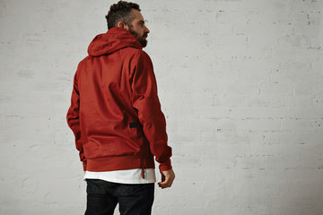 Back shot of a stylish bearded guy wearing a brick red anorak, black jeans and white t-shirt...