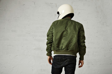 Back shot of a motorcyclist in white helmet and green bomber jacket isolated on white