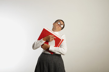 Tired looking female teacher in conservative clothes almost falls down under the weight of heavy...
