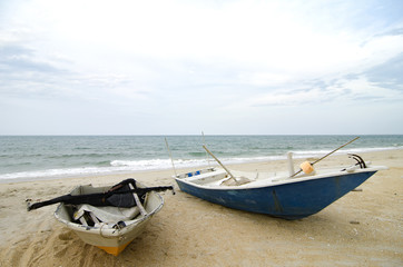 Naklejka premium fisherman boat stranded on the sandy beach and cloudy sky.