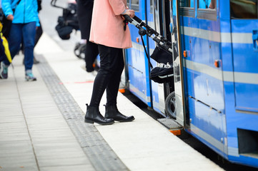 Woman with baby stroller entering tram
