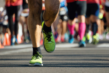 Marathon running in the light of evening, people feet on city road