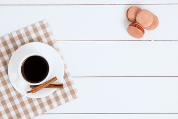 Obraz na płótnie Canvas Cup of coffee with cinnamon and macaroons on a white background.