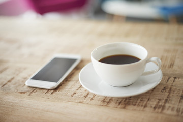 Fototapeta na wymiar Cup of coffee and phone on the desk