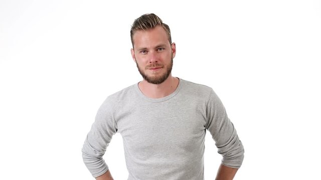Smiling man wearing a grey shirt with rolled up sleeves, standing in front of a white background.