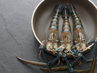 Three shrimp, prawn in the brown bowl with dark background