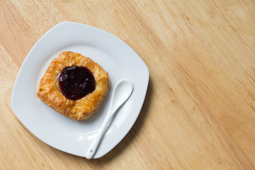 Danish blueberry pie with spoon in white plate on wooden table