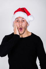 charmanter, junger Mann mit Dreitagebart und Weihnachtsmütze zeigt Weihnachts-Emotionen