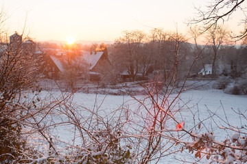 Winterlandschaft mit bedeckter Schneedecke bei aufgehender Sonne