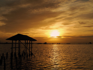Fototapeta na wymiar Beautiful sunset landscape orange golden sky above sea with silhouette of fish farms.