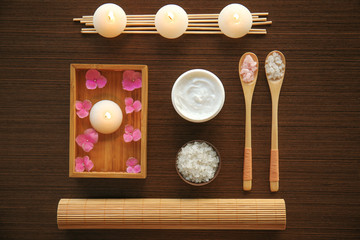 Spa set with nutrient cream and sea salt in spoons on wooden background