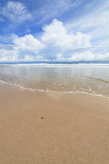 Fototapeta na wymiar Waves sand beach and clouds sunny day