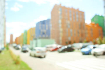 Blurred view of parked cars near modern colorful buildings