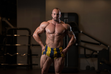 Fototapeta na wymiar Athlete Muscular Bodybuilder Posing In The Gym