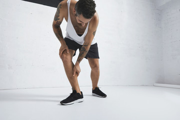 Athletic tattooed young man rubbing his injured during workout calf leg muscle © BublikHaus