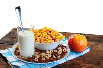 Corn flakes with glass of milk and fresh apple on old wooden table