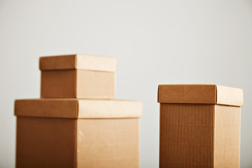 Blank unlabeled brown corrugated cardboard boxes with covers arranged in a beautiful composition isolated on white