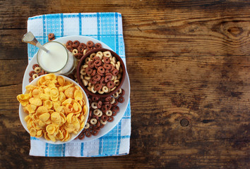 Corn flakes and glass of milk on old wooden table