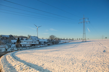 Winterlandschaft mit Oberleitungen f&uuml;r Strom im Gegenlicht bei blauem Himmel