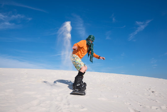 Snowboarder, wearing a scarf landed after trick on a sand slope
