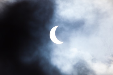 Naklejka na ściany i meble Partial solar eclipse through clouds