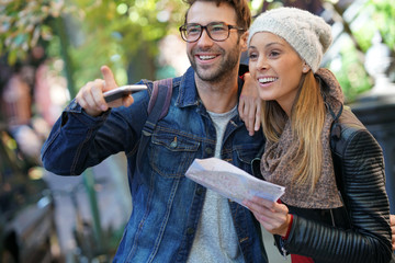 Trendy couple using smartphone and city map of New York on their journey
