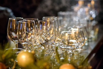 Glasses, forks, knives, napkins and decorative flower on a table served for dinner in cozy restaurant.