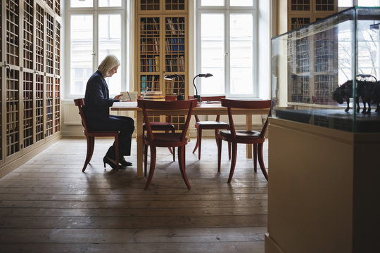 Side view of senior female lawyer reading book in library