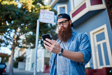 bearded hipster using smartphone in san francisco